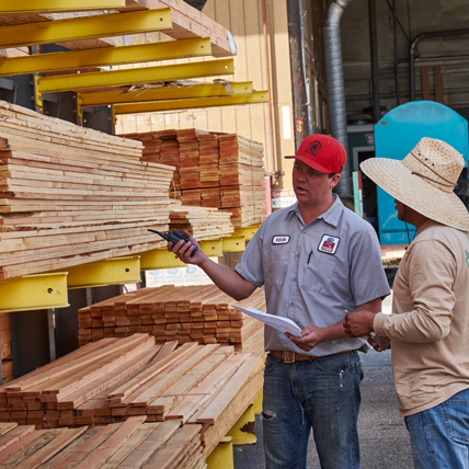 A Ganahl lumberyard employee assisting a customer pick out lumber in the yard. 